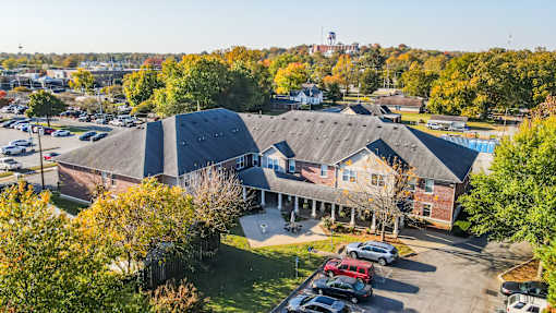 A parking lot with cars and a building with a flag on top.