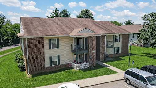 A house with a brown roof and a white car parked in front.