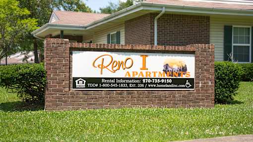 A sign for Rent Apartments in front of a house.