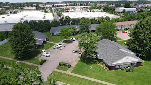 A parking lot with cars and a building with a grey roof.