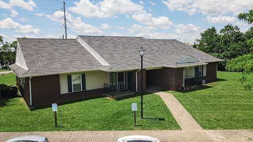 A house with a brown roof and a green lawn in front.