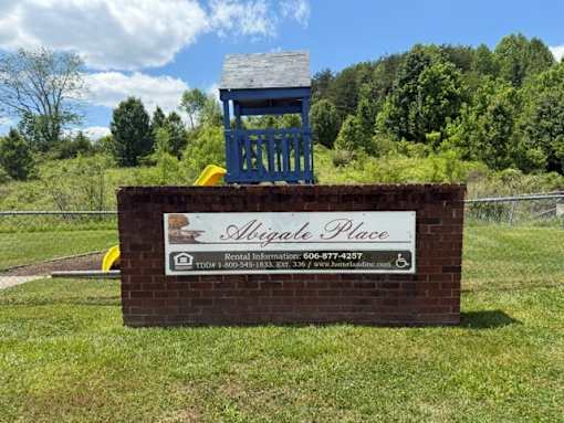 A sign for Abigale Place rental information is displayed on a brick structure.