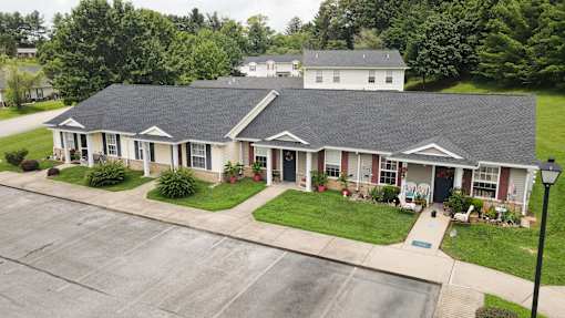 A house with a grey roof and white walls with a green lawn in front.