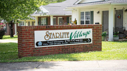 A sign for Stadium Village in front of a house.