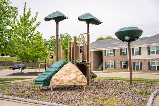 A playground with a green slide and two green umbrellas.