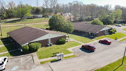 A parking lot with a building and cars in front.