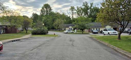 A street view of a residential area with cars parked on the side of the road.