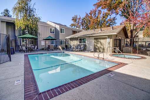 A swimming pool surrounded by a fence and a gazebo in the background.