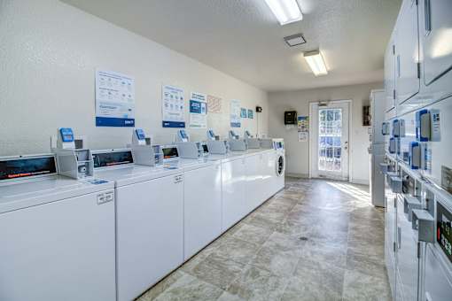 A laundromat with washers and dryers lined up.