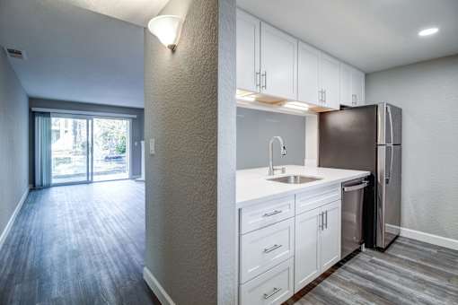 A kitchen with white cabinets and a stainless steel refrigerator.