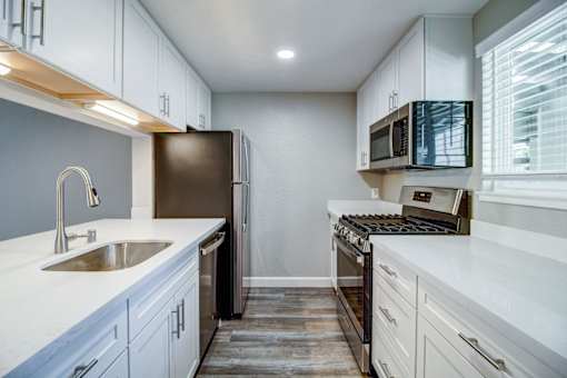 A kitchen with white cabinets and a black refrigerator.