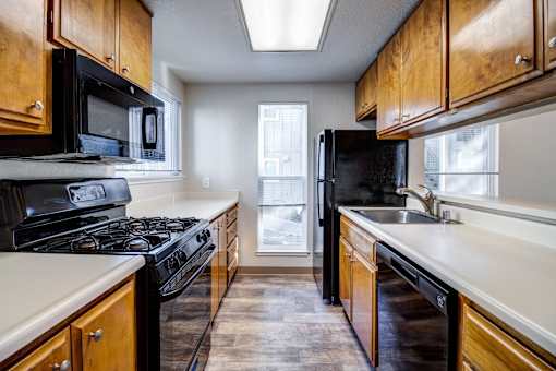 A kitchen with black appliances and wooden cabinets.