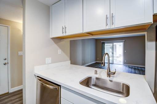 A kitchen with a white counter top and a stainless steel sink.