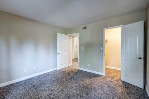 A room with carpeted floor and two white doors.
