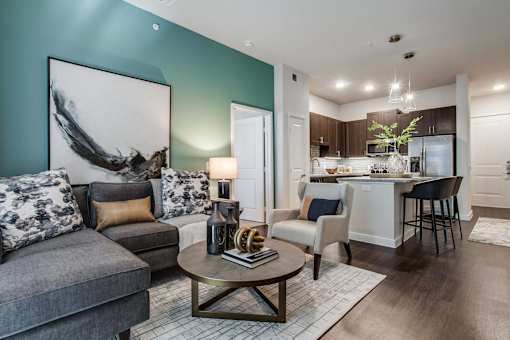 Contemporary apartment living room with stylish seating, modern lighting, and seamless flow into the kitchen and dining area.
