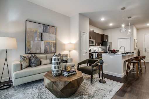 Contemporary apartment living room with stylish seating, modern lighting, and seamless flow into the kitchen and dining area.