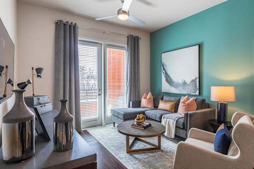 Modern apartment living room with sectional sofa, coffee table, accent wall, and patio access door.