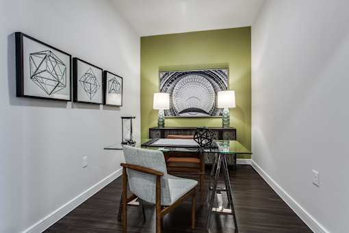 Modern home office with desk, ergonomic chair, and natural light from large windows.
