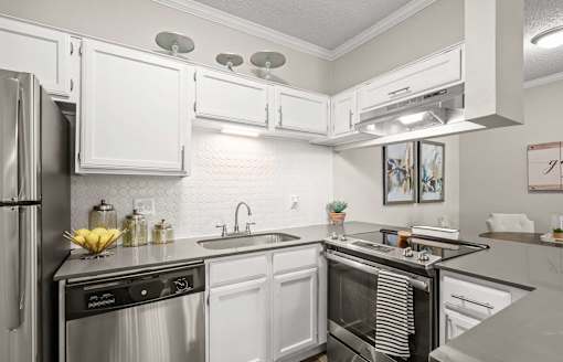 A modern kitchen with white cabinets and stainless steel appliances.