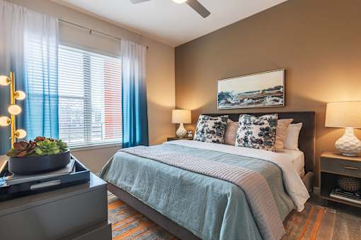 Spacious bedroom with plush carpeting, large windows, ceiling fan, and modern décor.
