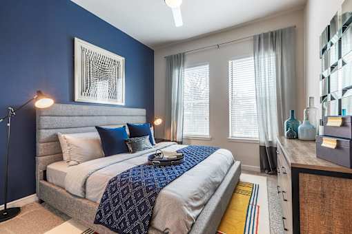 Spacious bedroom with plush carpeting, large windows, ceiling fan, and modern décor.