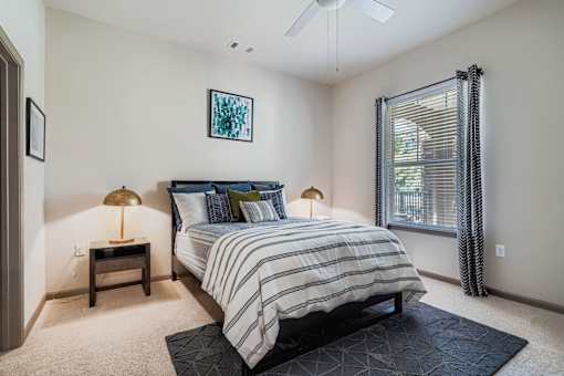 A bedroom with a bed, nightstands, and a ceiling fan.