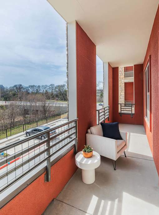 Private apartment patio with outdoor seating and views of the landscaped community grounds.