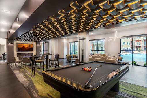 Spacious resident game room featuring a pool table, poker table, lounge seating, and entertainment amenities.