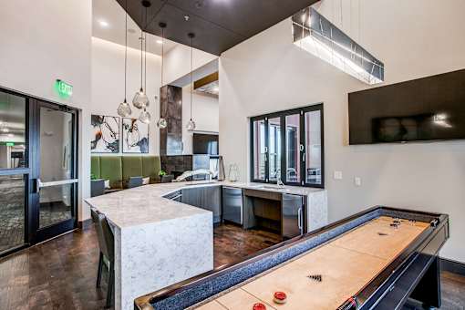 Resident lounge featuring a shuffleboard table, comfortable seating, and modern clubhouse amenities.