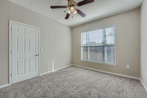 A room with a ceiling fan and a window with blinds.