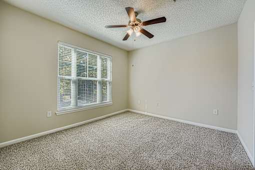 A room with a ceiling fan and a window with blinds.