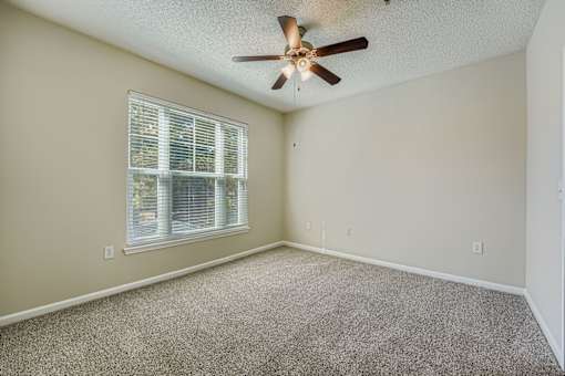 A room with a ceiling fan and a window with blinds.