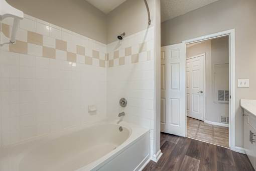 A bathroom with a tub and a doorway leading to another room.