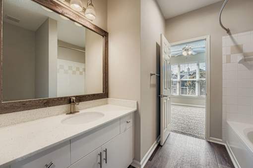 A bathroom with a sink, mirror, and bathtub.