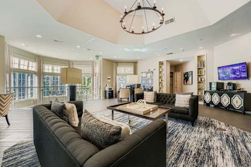 A modern living room with a large grey sofa and a chandelier.