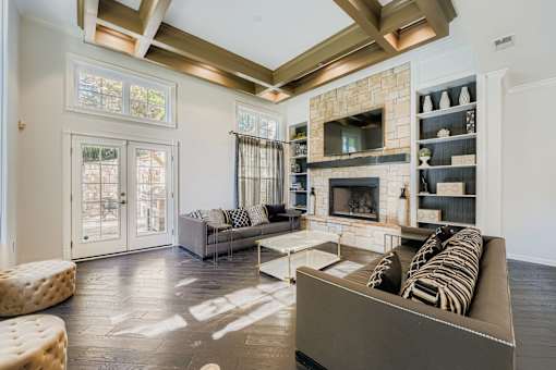 A living room with a stone fireplace and a grey couch.