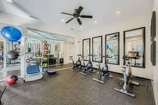 A spacious gym with a variety of exercise equipment and mirrors on the wall.