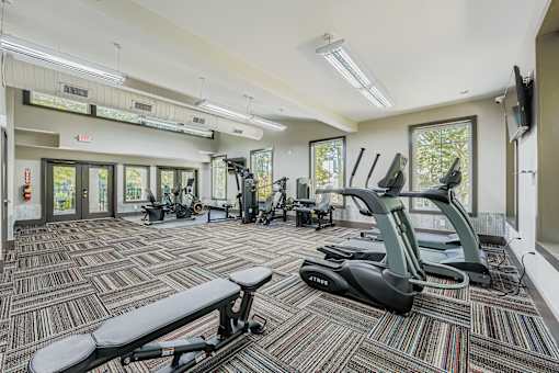 A gym with a variety of equipment including treadmills, exercise bikes, and weights.
