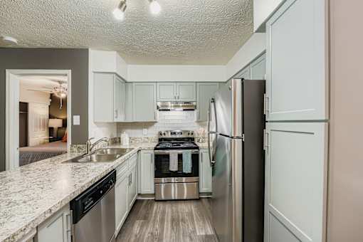 A kitchen with a refrigerator, sink, and stove.