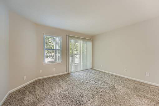 A room with a carpeted floor and a sliding glass door.