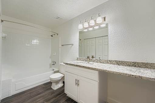 A white bathroom with a toilet, sink, and mirror.