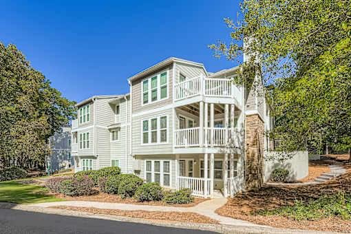 A large white house with a balcony and a tree in front.