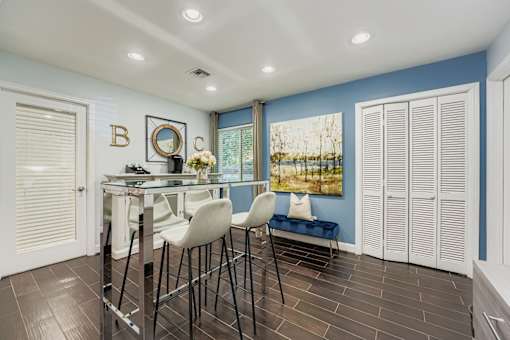A dining area with a glass table and white chairs.