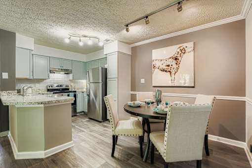 A kitchen with a table and chairs and a painting of a giraffe.