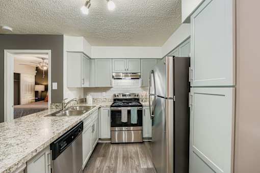 A kitchen with a refrigerator, sink, and stove.