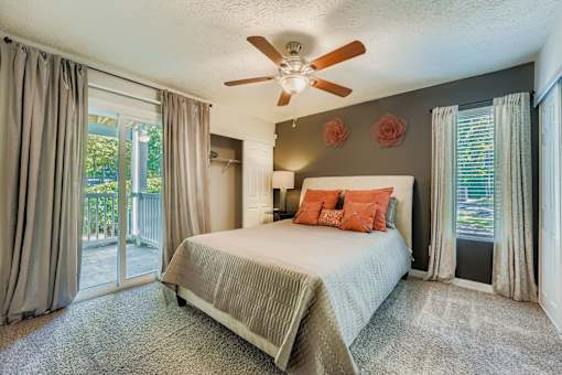 Bedroom with a bed, a ceiling fan, and a sliding glass door.