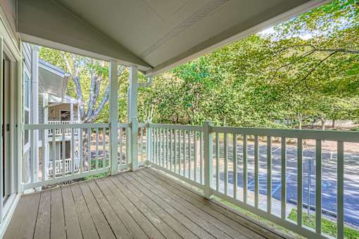 A white balcony with a wooden floor and a white railing.
