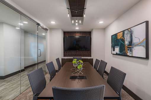 Modern on-site conference room with large meeting table, executive chairs, and wall-mounted display screen.