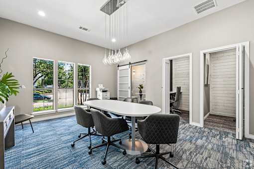 A conference room with a white table and grey chairs.