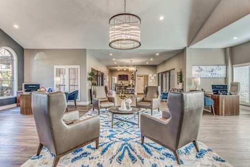 A large, modern living room with a central rug and a chandelier.